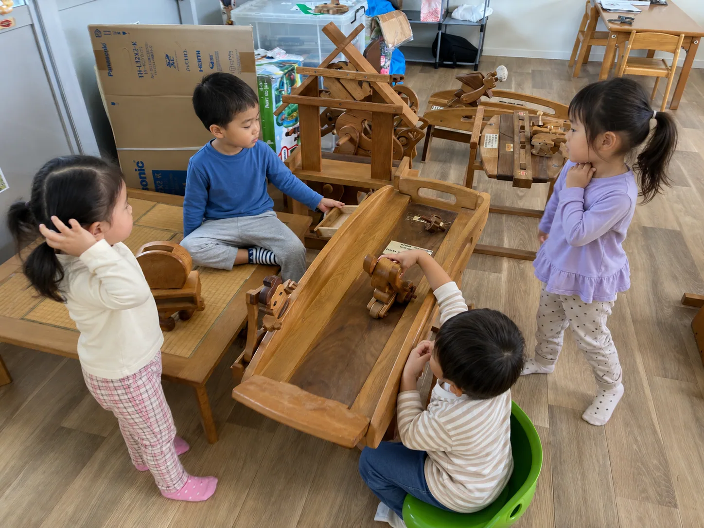 木のおもちゃを囲んで遊び方を考える子どもたち